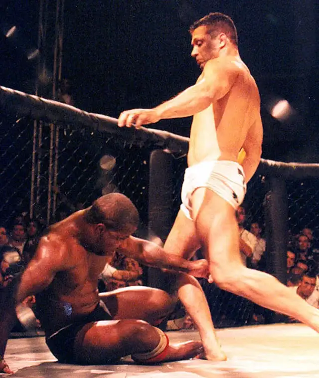 Renzo Gracie chuta o oponente caído Eugenio Tadeu no Pentagon Combat Vale Tudo — este cenário exato de chutar um lutador caído agora é proibido pela WKF em competição de karatê desde 2026. Domínio público via Wikimedia Commons