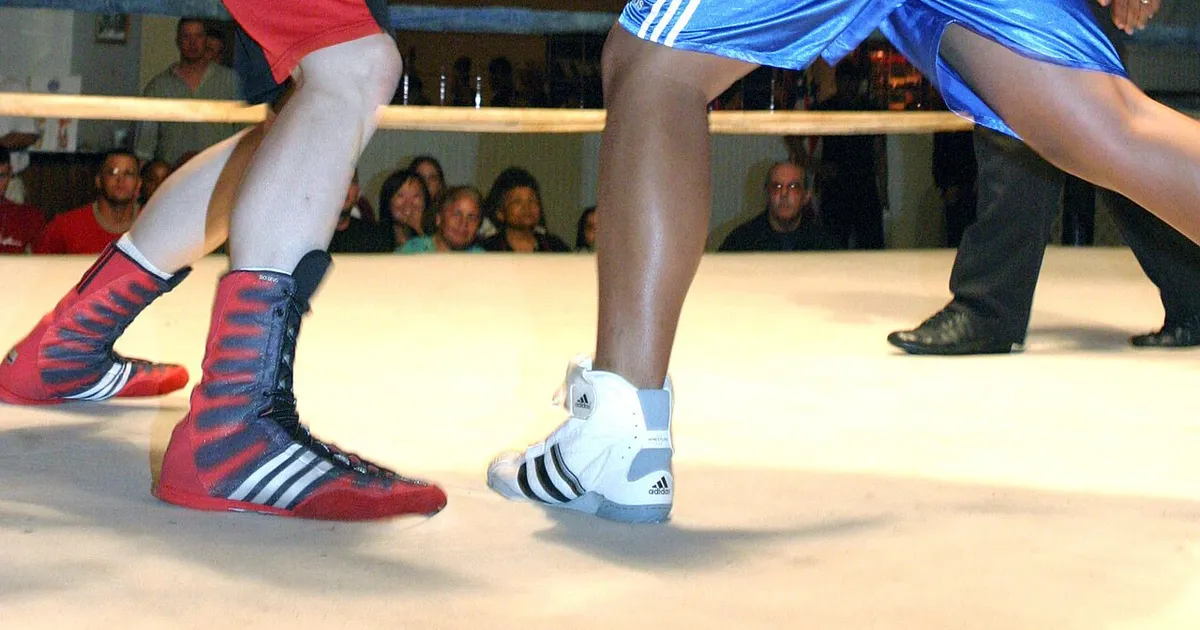 Trabalho de pernas no boxe — boxeador ortodoxo demonstrando a sequência de passo-arrastar (step-drag), pivô (pivot) e saída de ângulo (angle-off) com controle do centro do ringue