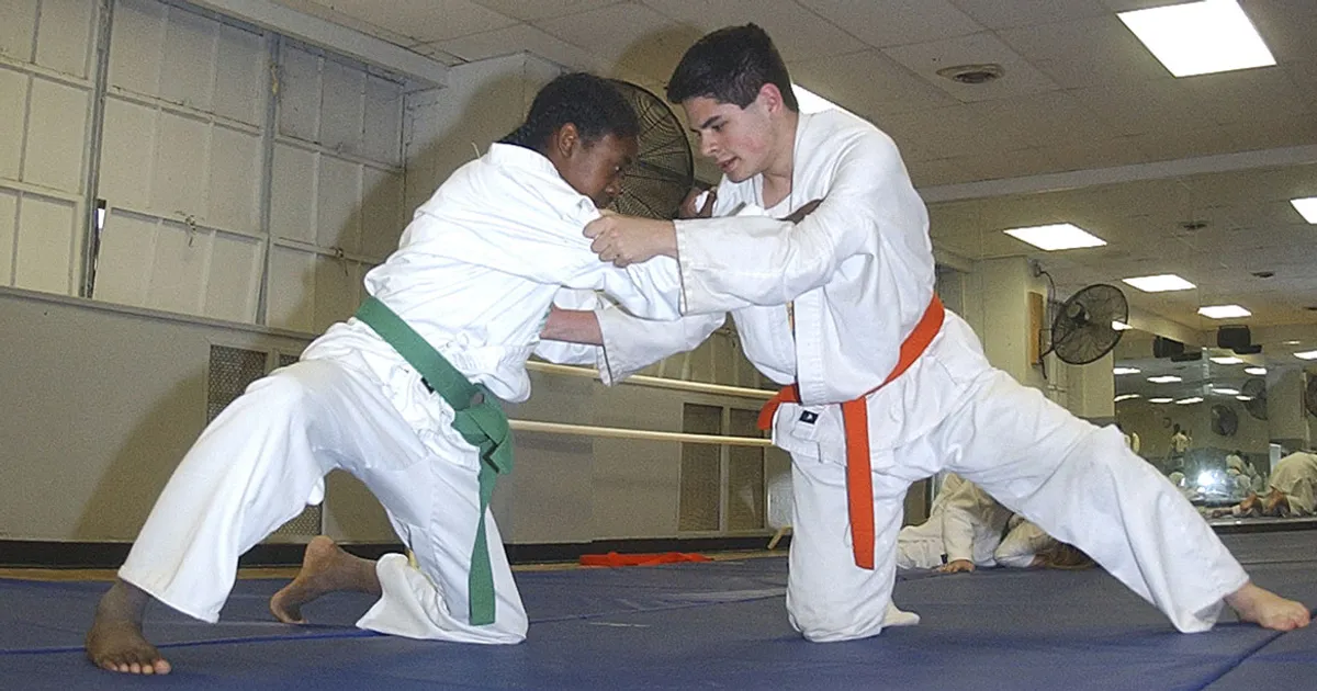Judo ne-waza — tori aplica kesa-gatame (llave de bufanda) a uke en un entorno competitivo, demostrando la posición fundamental de control en suelo del sistema Kodokan
