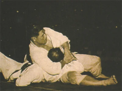 Masahiko Kimura демонстрира kesa gatame (захват-шал) — позицията за контрол на земята, от която се извършват много атаки с Kimura lock. Обществено достояние чрез Wikimedia Commons