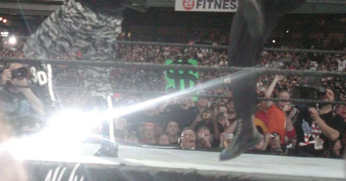 Luchador ejecutando un derribo de doble pierna con contacto del hombro en el abdomen del oponente y ambos brazos unidos detrás de los muslos.