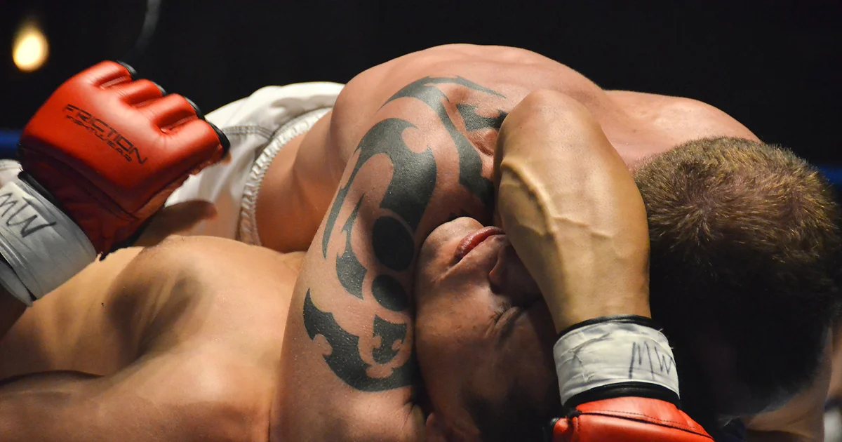 Arm triangle choke from side control — opponent's near-side arm pinned between attacker's head and arms, bilateral carotid compression from shoulder and bicep